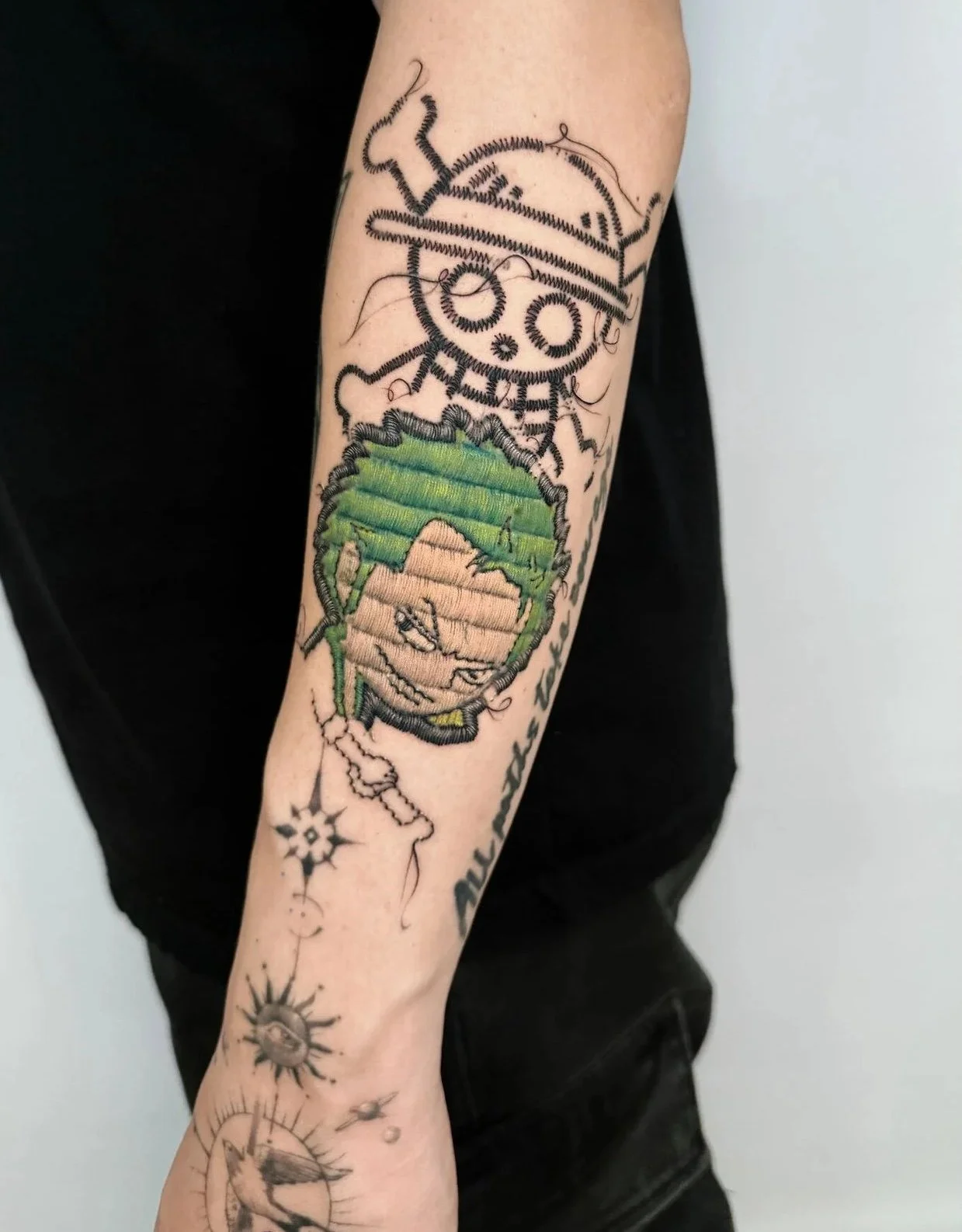 person's arms with a skeleton with a green hair zoro