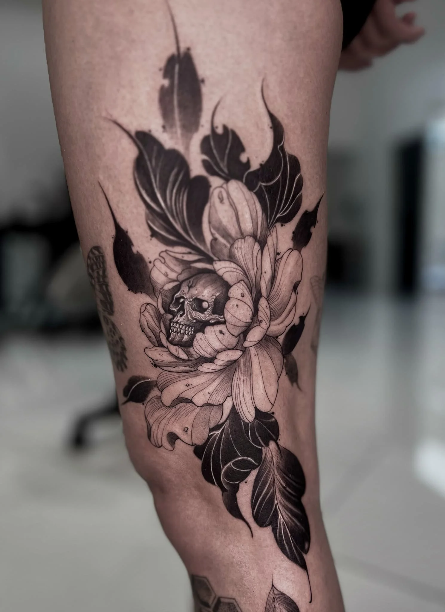 trevor-artist-skull-flowers-leaves-thigh-tattoo-black-and-gray.jpg