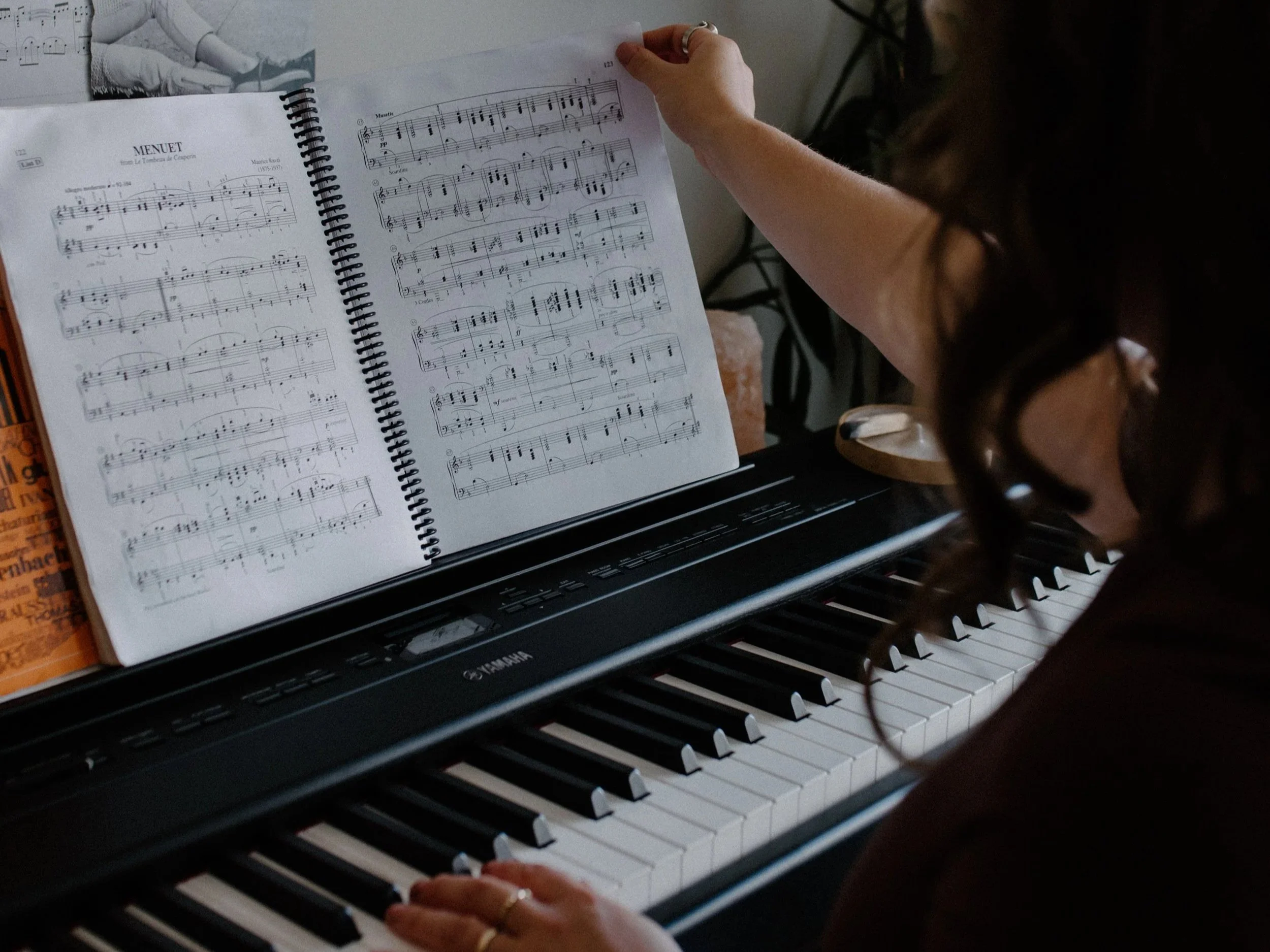 Olivia Apara, music therapist, music teacher, at the piano flipping through classical sheet music.