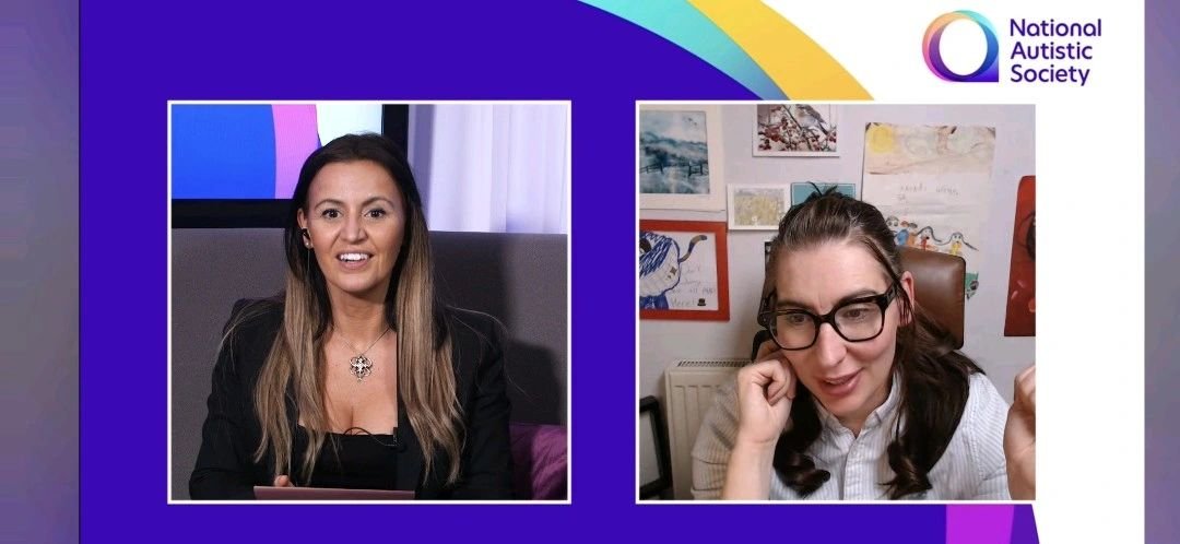 Screenshot of two women during a virtual meeting, one with long dark hair and a black blazer, the other with glasses and dark hair, sitting in a room with colorful artwork on the wall, with the logo of the National Autistic Society in the top right corner.
