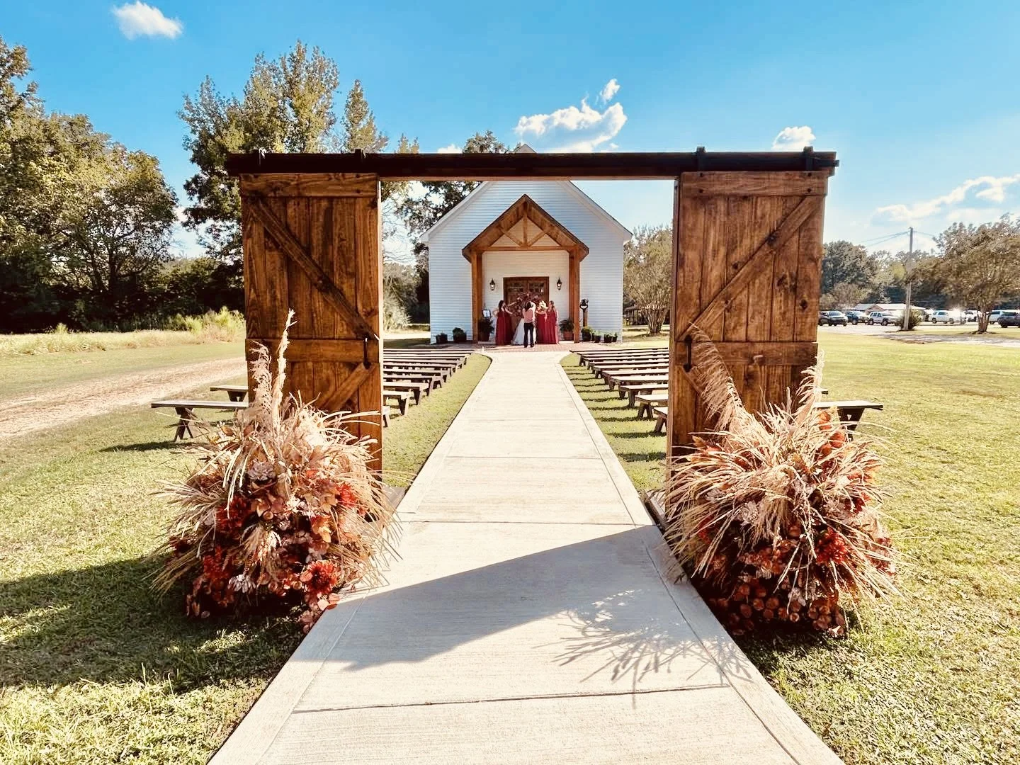 Barn door ceremony arch with fall florals leading to Hopewell Chapel at Alvastage Acres