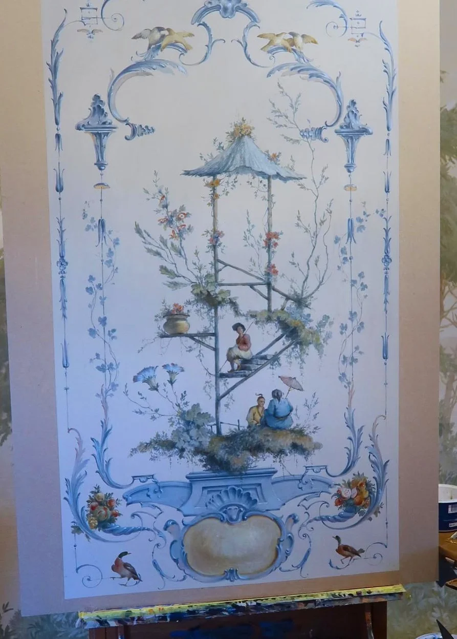 A detailed decorative painting featuring a tree with a thatched roof gazebo and small figures sitting on its branches, surrounded by ornate blue and white floral and scroll motifs, with birds at the bottom.