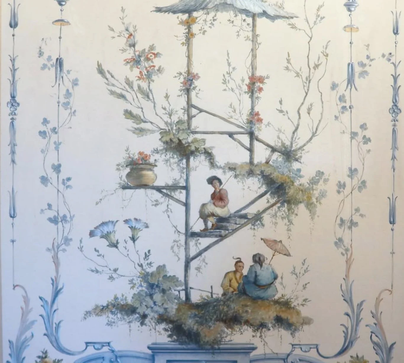 A detailed mural depicting people sitting on a ladder-like structure surrounded by plants and flowers, with decorative borders.
