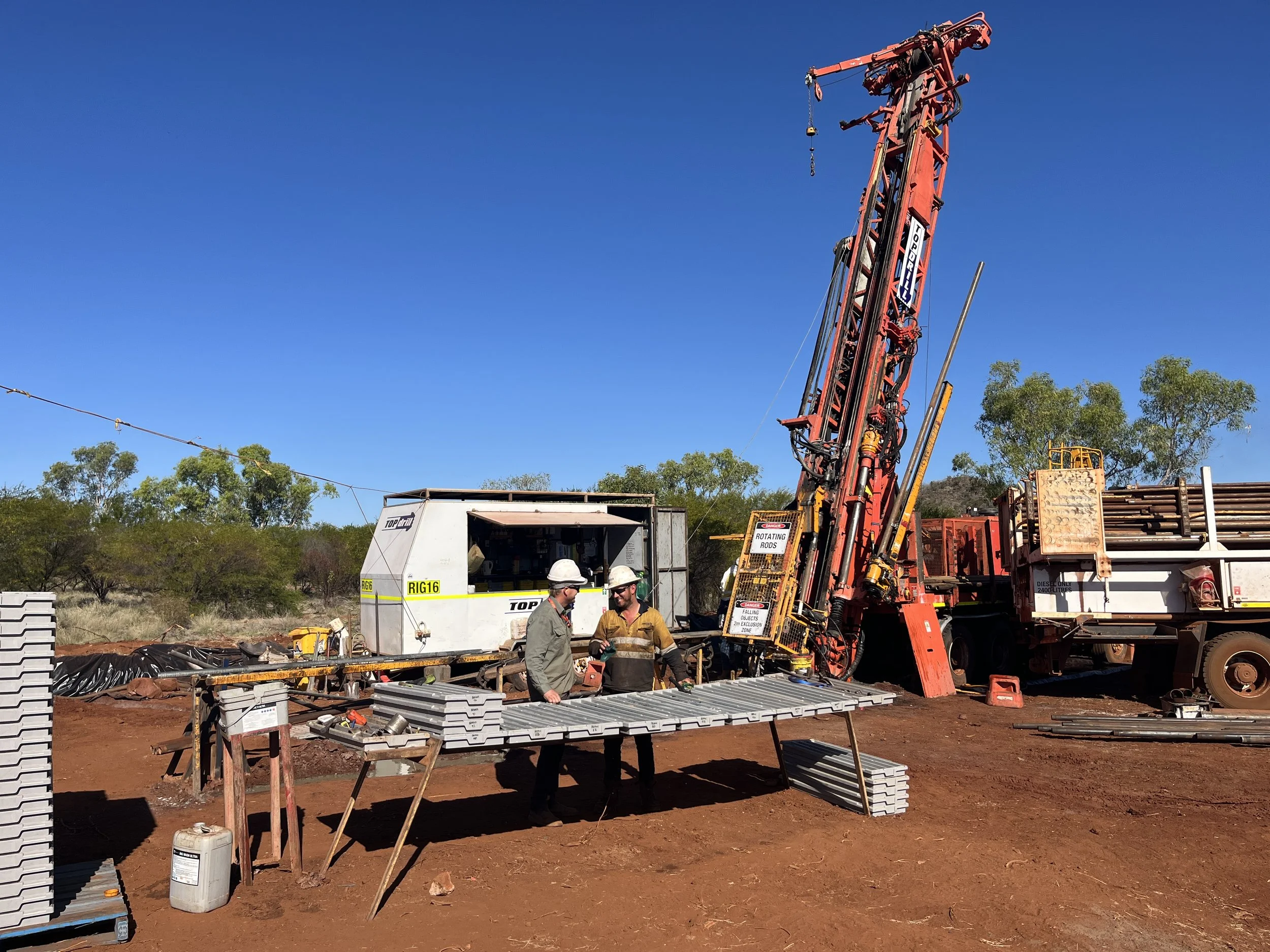 Mining operation site with drilling rig and workers handling core samples