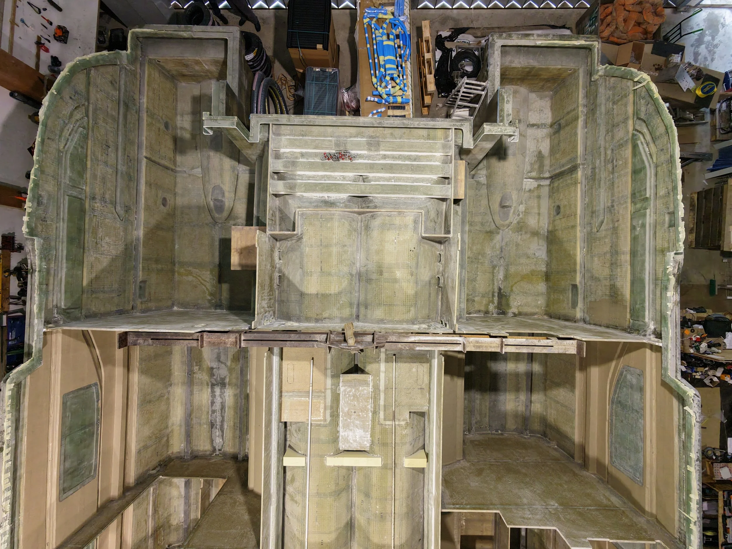 Top-down view of the interior of an unfinished hul of a boat showing its compartments and structural framework.