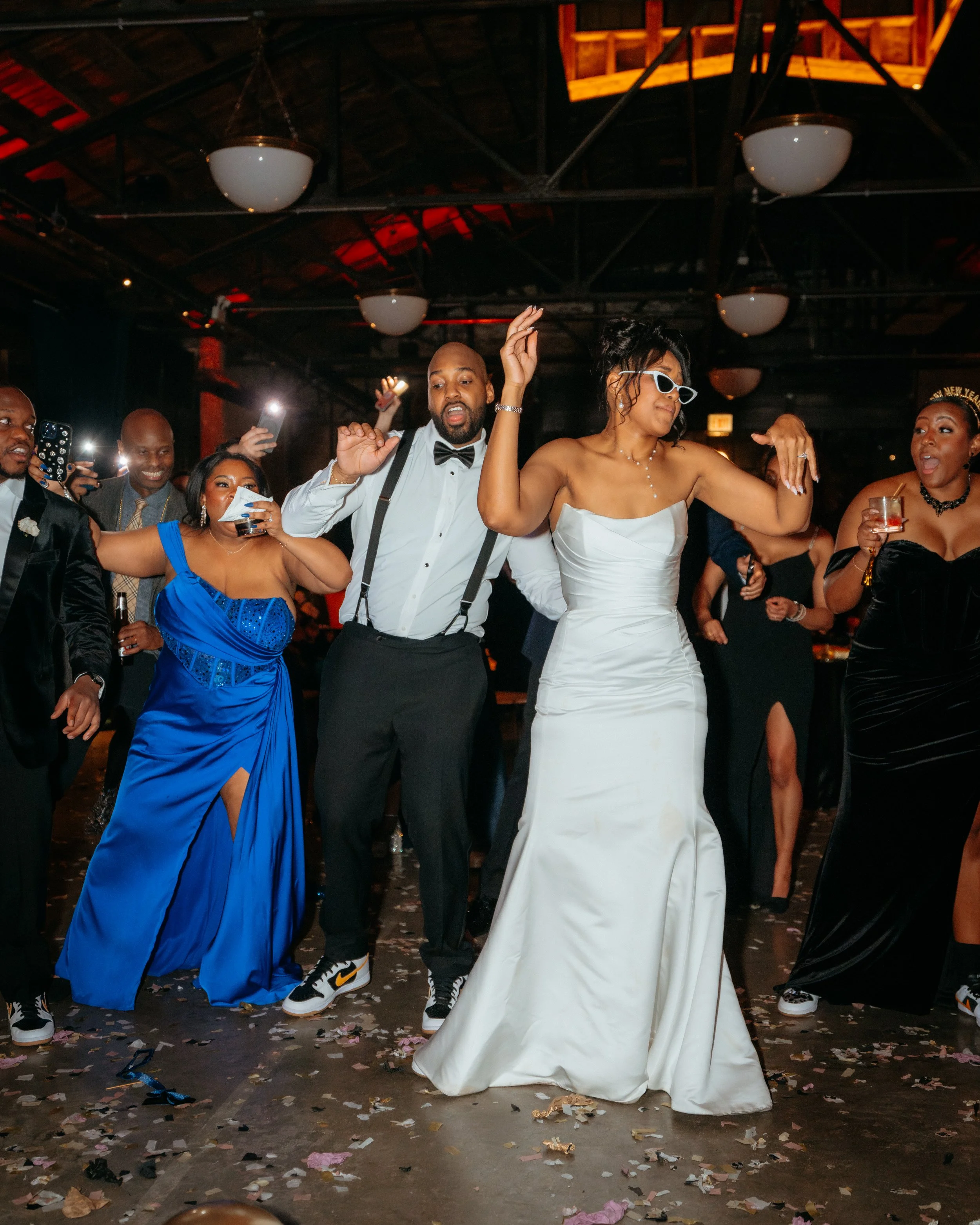 Black bride and groom dancing on the dance floor surrounded by their wedding guests all celebrating in formal attire