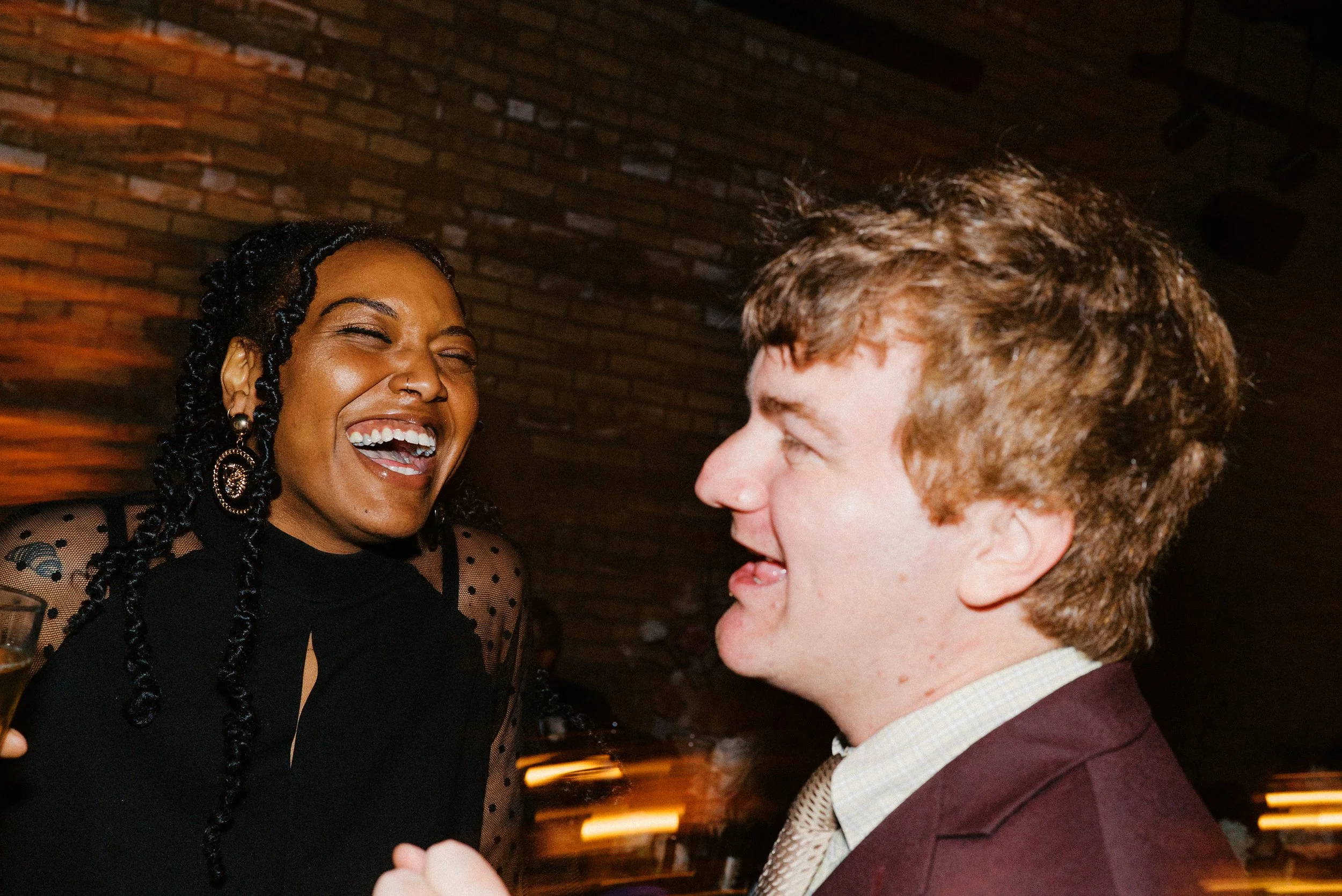 Two wedding guests sharing a joyful laugh on the dance floor, capturing the fun atmosphere Total Harmony Entertainment creates at Chicagoland weddings