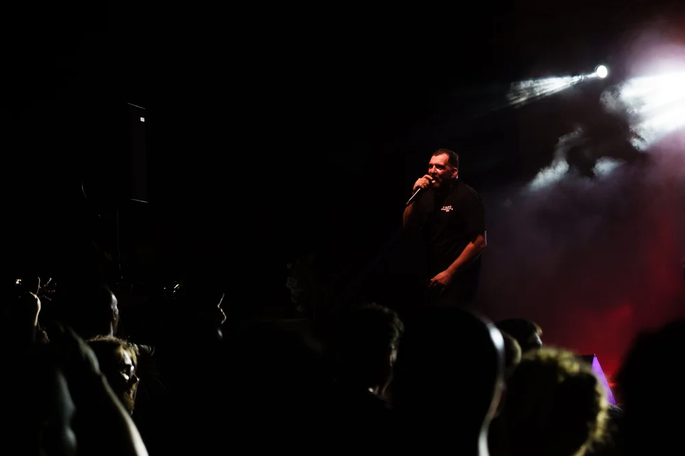 Anser and the audience in a wide, dark concert scene with overhead spotlights.
