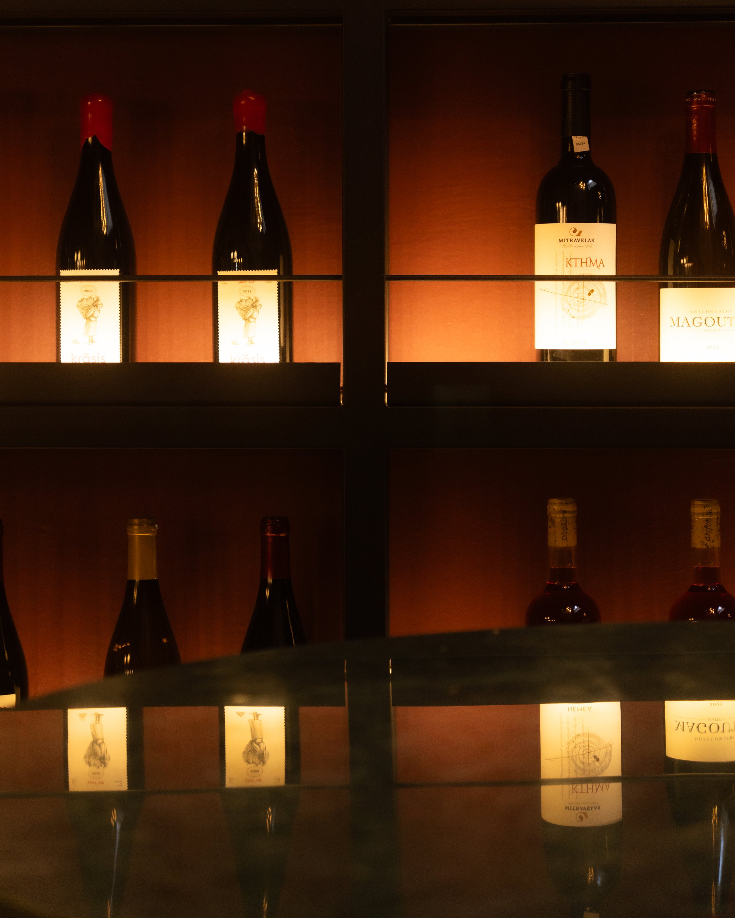 Wine bottles arranged on softly illuminated wooden shelves.