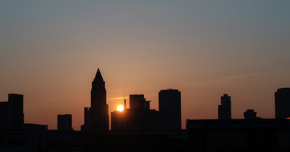 The sun setting behind a silhouetted city skyline.