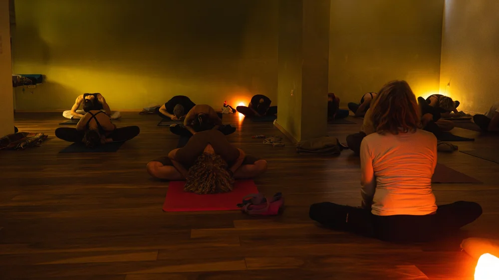The yoga group seated on mats in a softly lit studio.