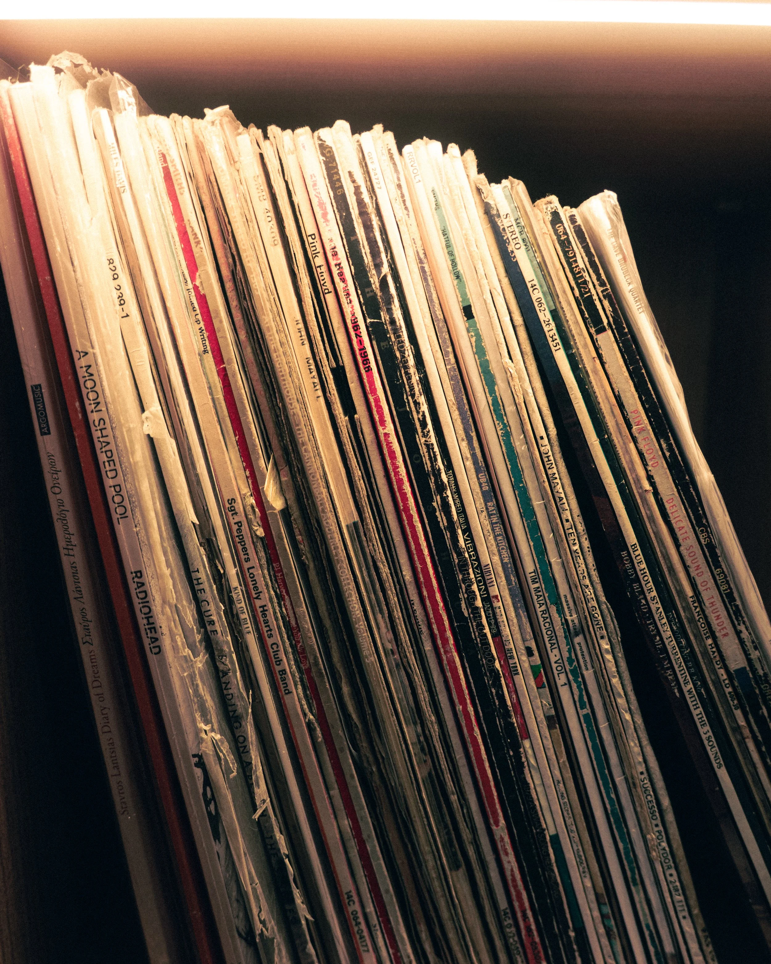 A close view of vinyl records on a warmly lit shelf.