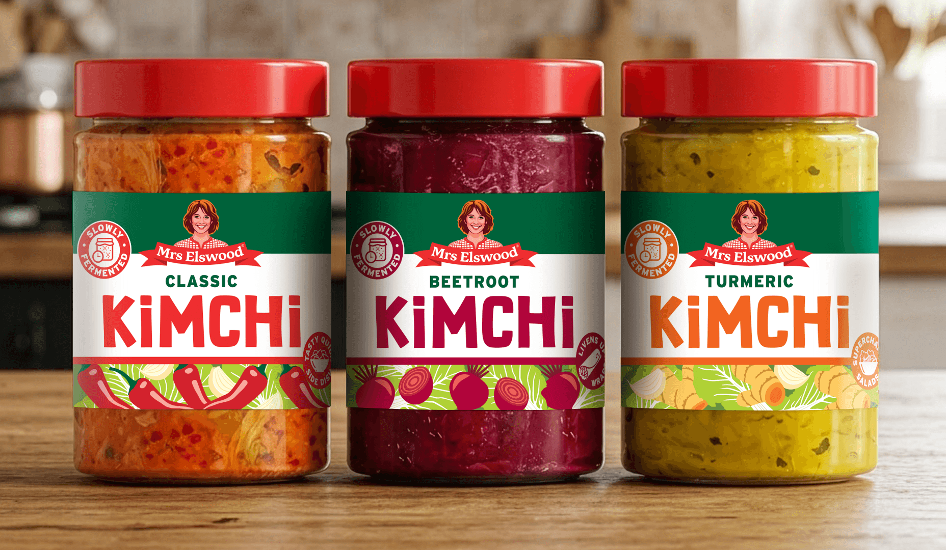 Three jars of Mrs. Elswood kimchi with different flavors: classic, beetroot, and turmeric, on a wooden surface in a kitchen setting.