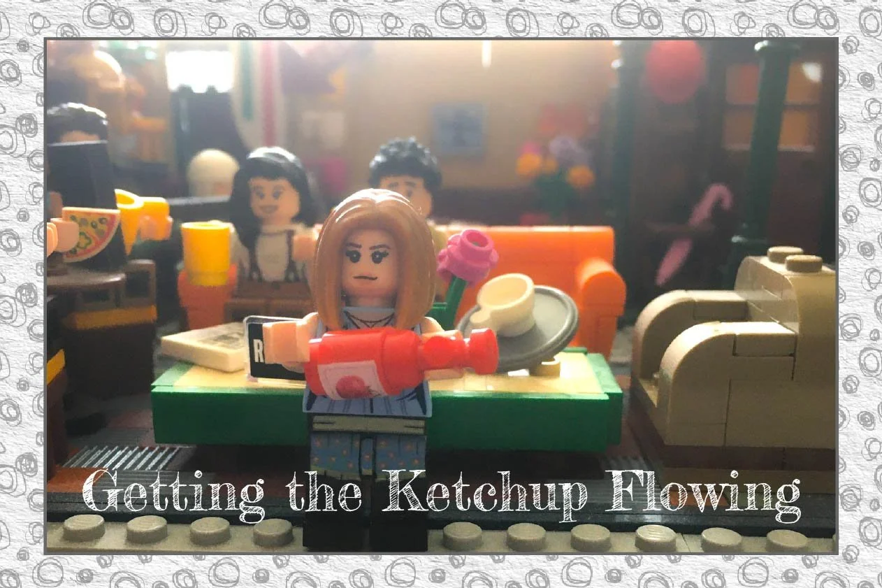 Grey scribbles on a light grey background form a boarder around the image.  In the centre is a thin grey boarder around an image of Lego Rachel from Friends holding a ketchup bottle