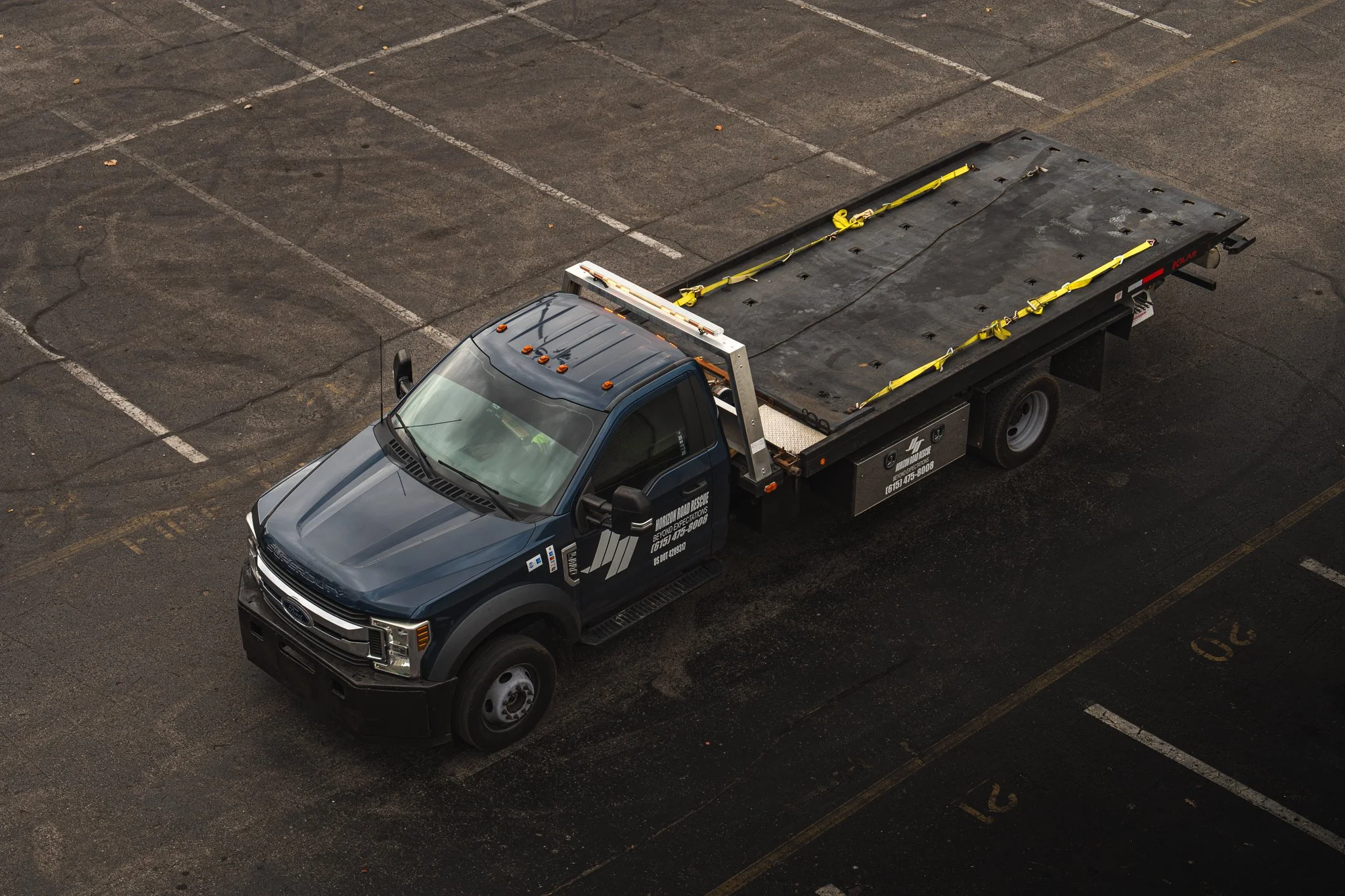 Flatbed truck parked in an empty lot, aerial view.