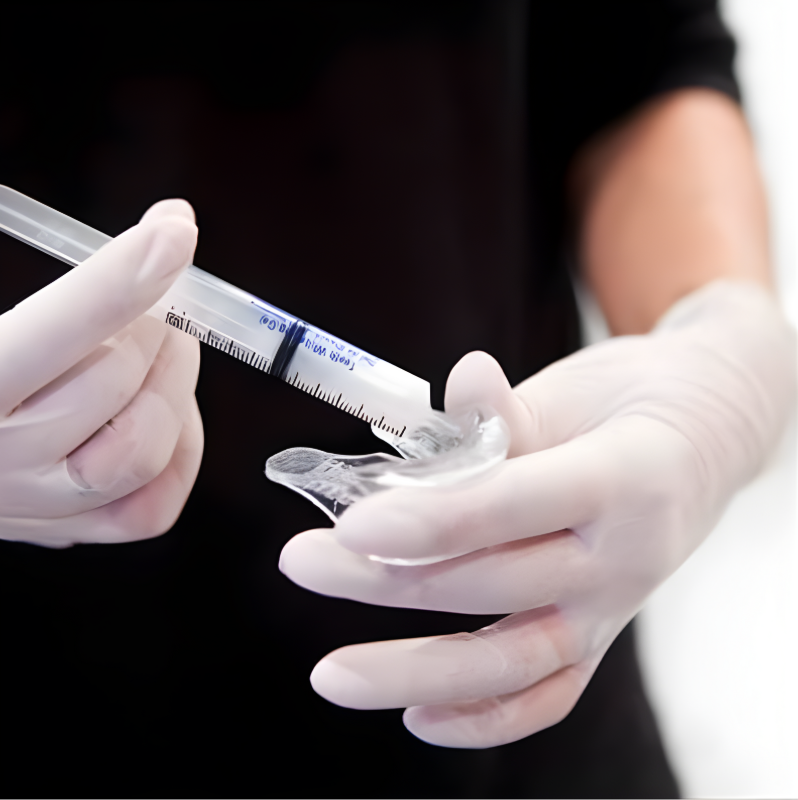 A medical professional in white gloves preparing a syringe with a clear substance for injection.