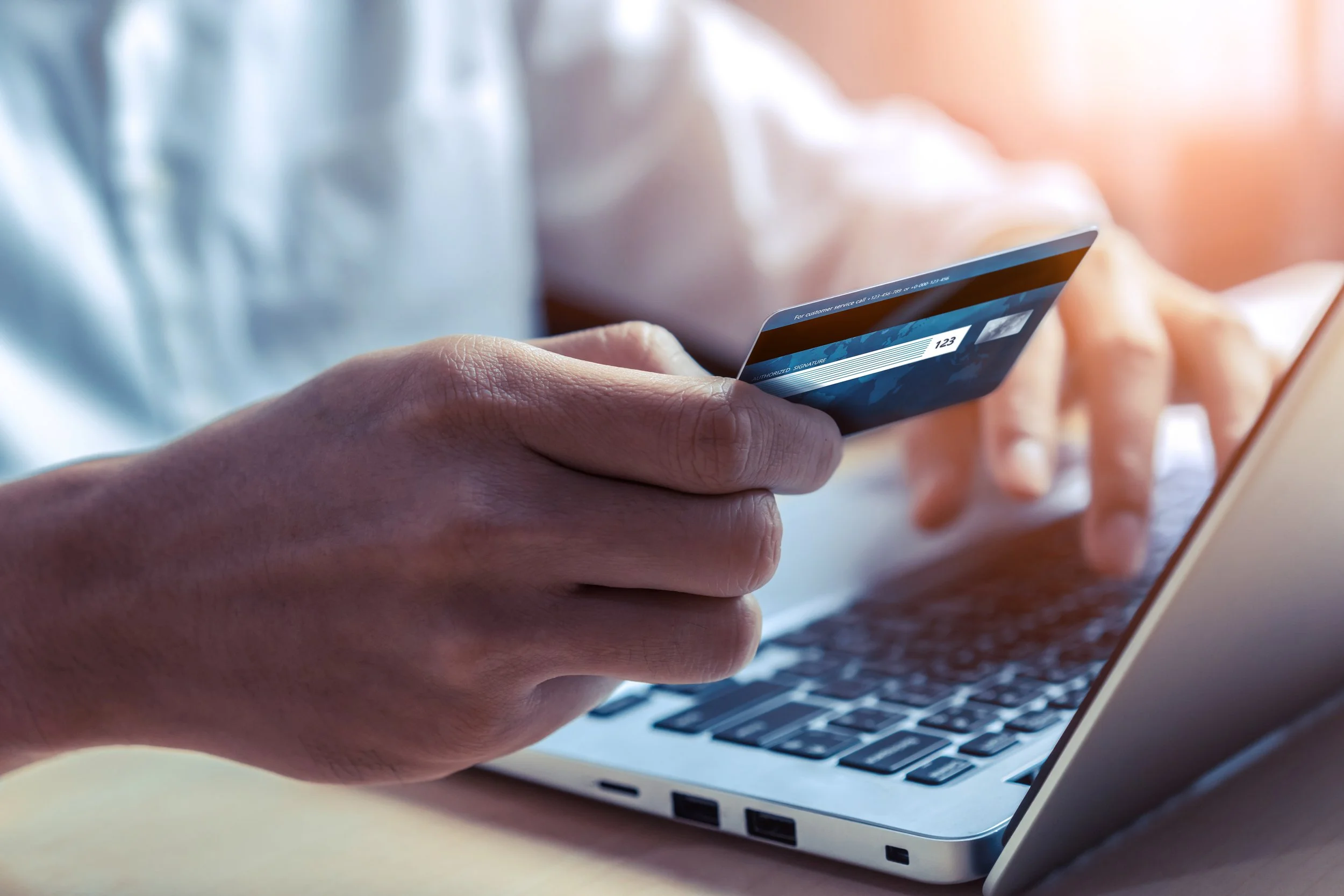 Person holding a credit card while using a laptop.