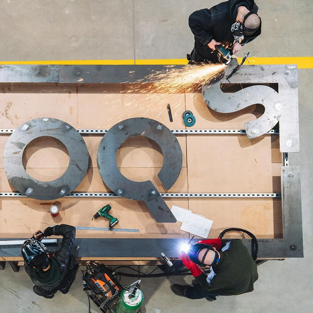 Workers making metal lettering