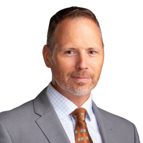 Hunter Johnson in a gray suit and orange patterned tie on a white background.