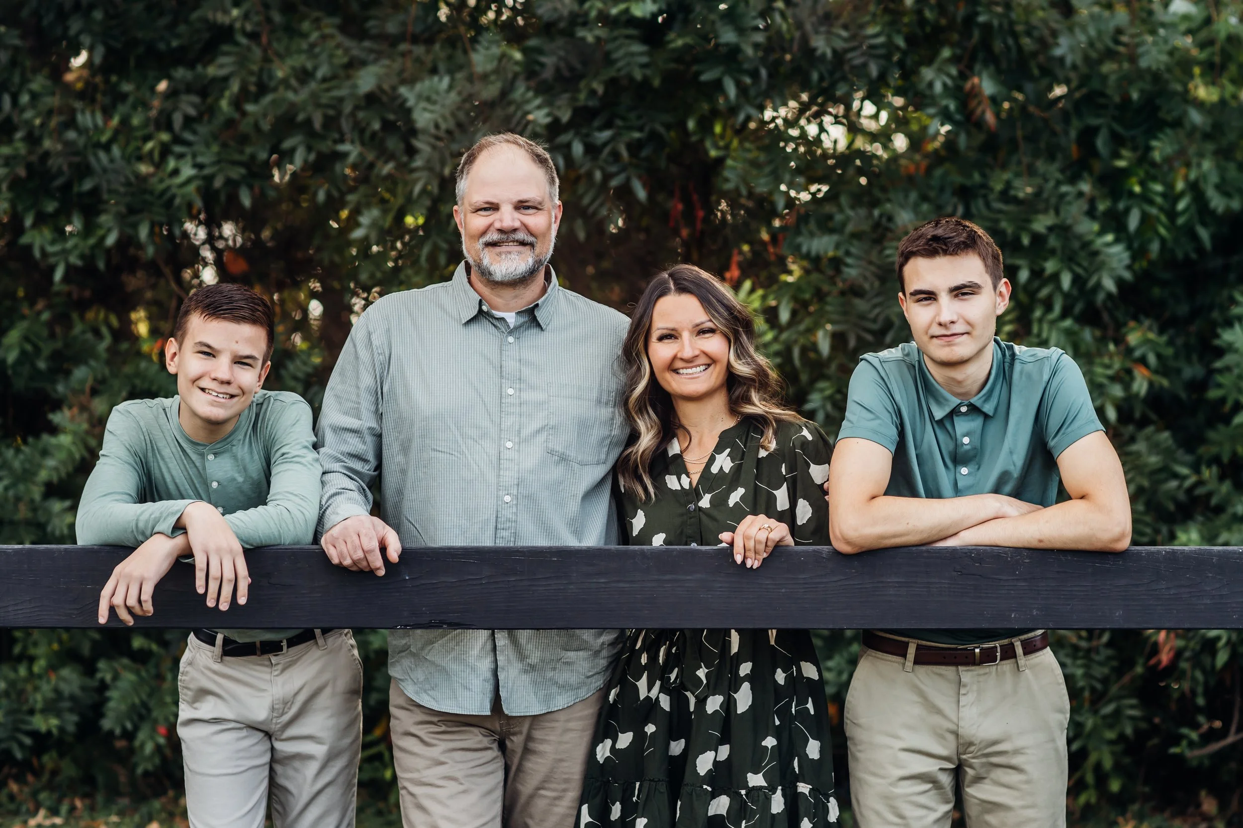 Family lean on a fence for a family photo