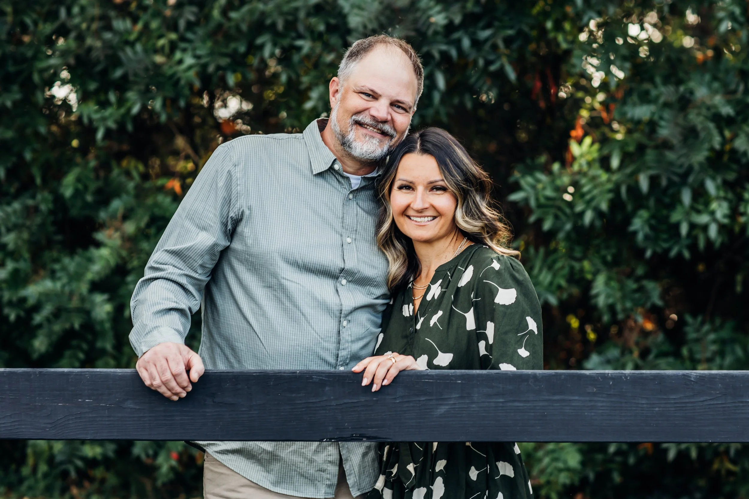 Parents pose on a fence to update their family photos