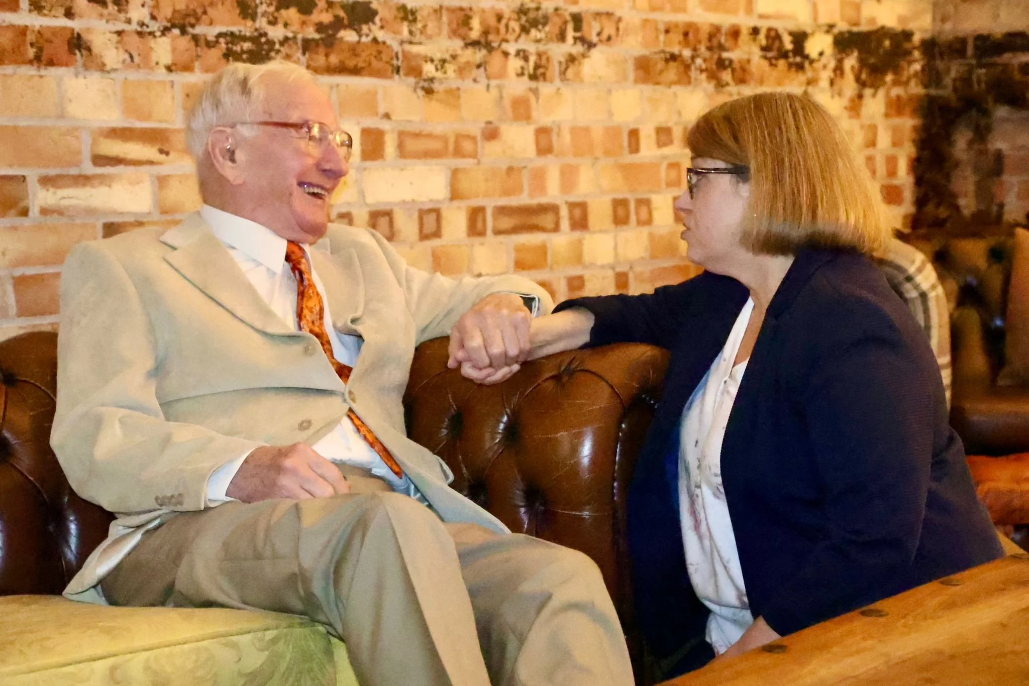 Elderly wedding guest enjoying the reception with discrete assistance from a professional wedding guest chaperone.