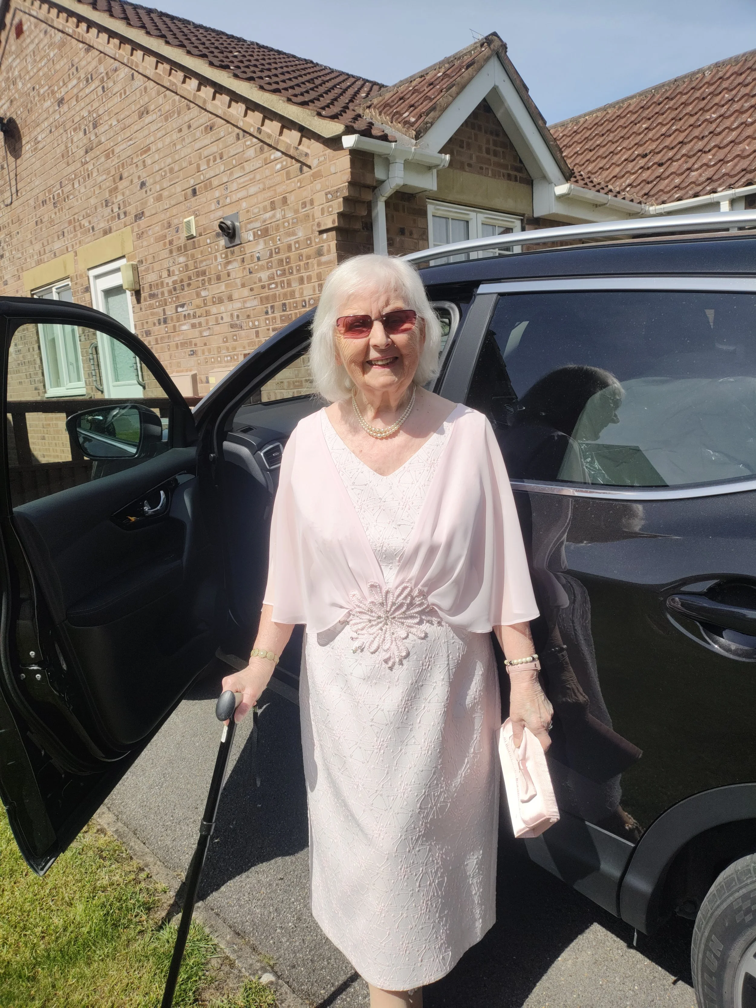 Grandmother being supported home to home by professional carer.