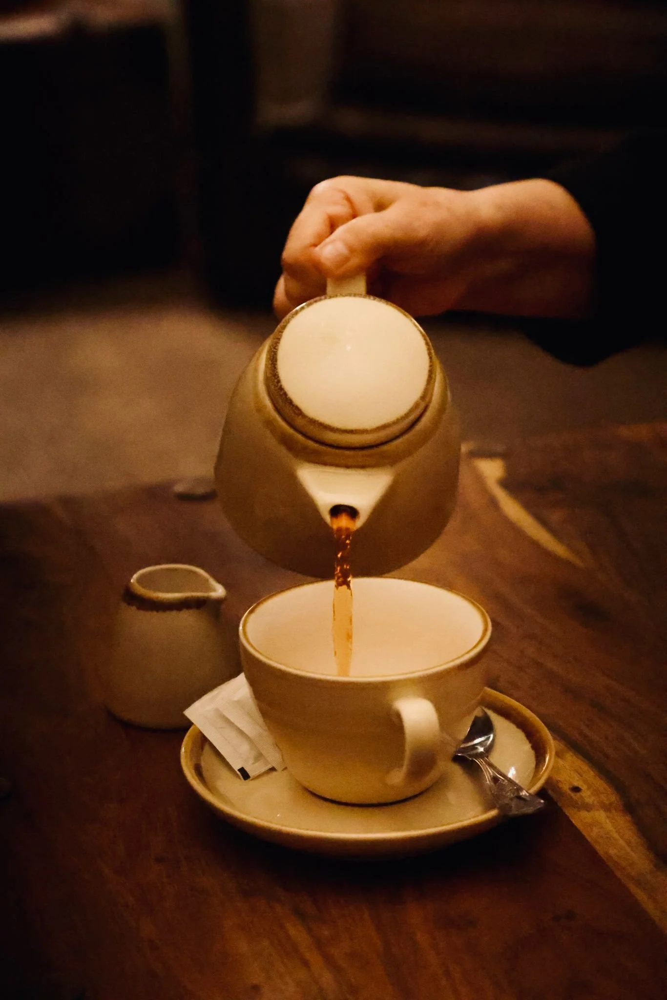 A cup of tea being poured from a teapot in quiet and peaceful surroundings