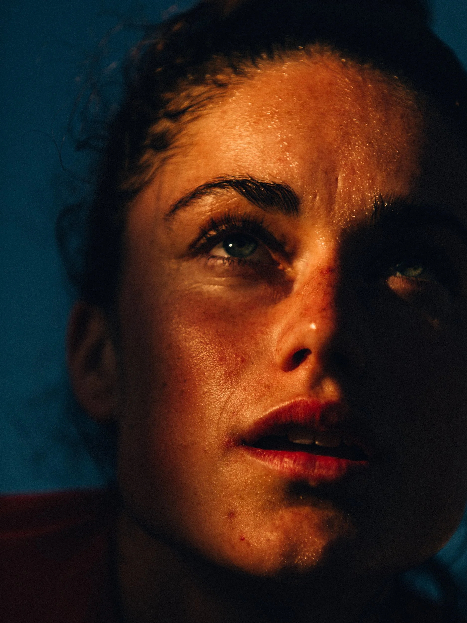 Close-up of a person's face illuminated by warm light, showing sweat and focus.