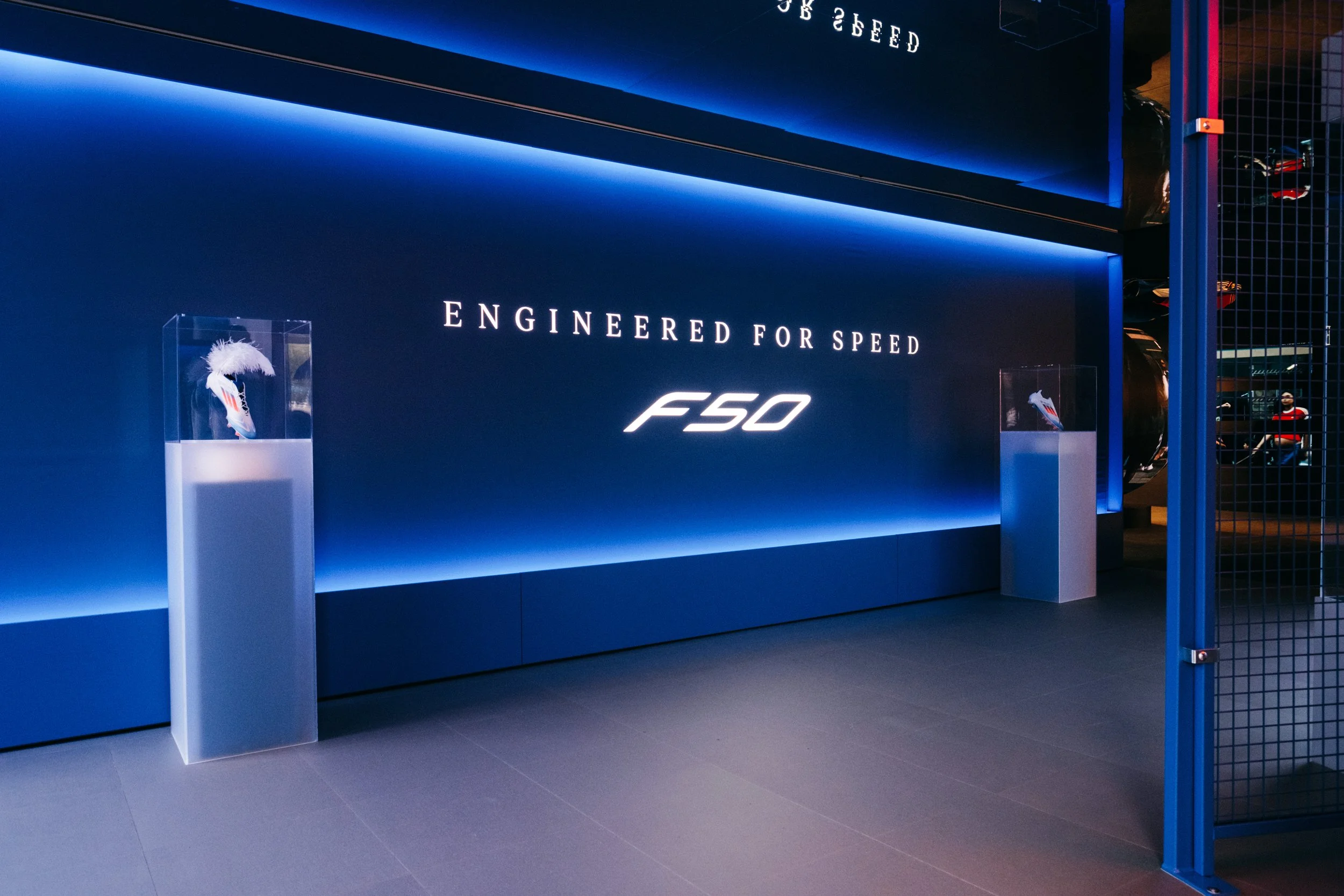 Exhibit display with illuminated blue background and text reading 'Engineered for Speed F50,' featuring two framed items on pedestals.