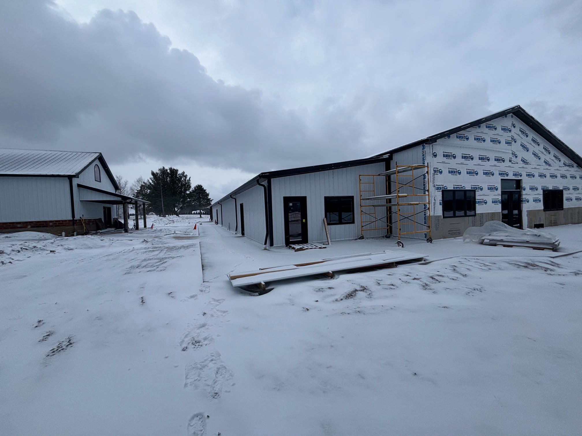 Snow-covered construction site with two buildings and scaffolding