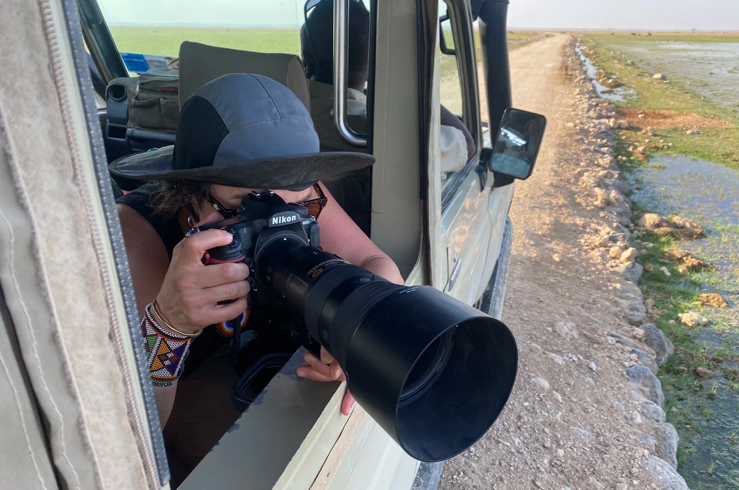 Selina photographing wildlife from a safari vehicle with a long telephoto lens.