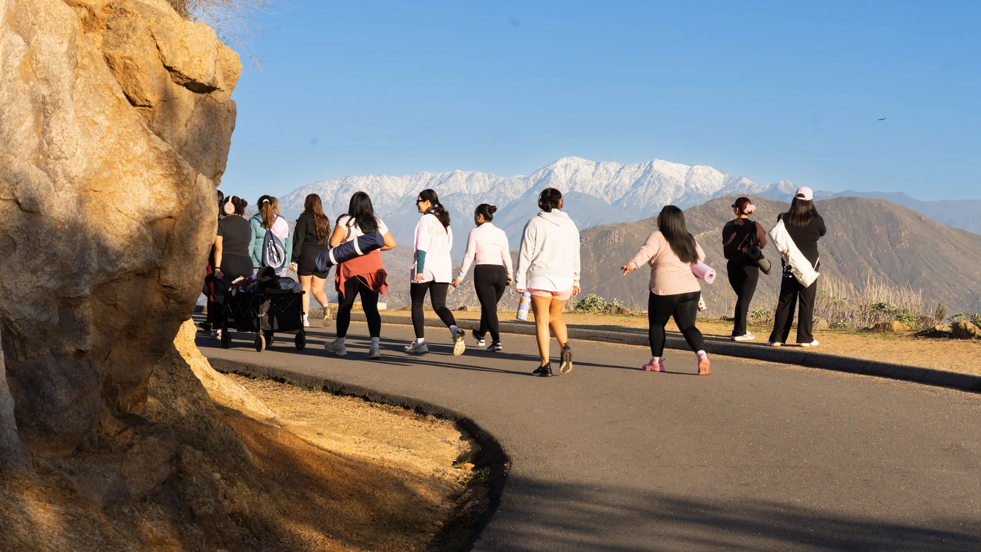 women of IE women hiking group with snow peaks in the distance carrying yoga mats