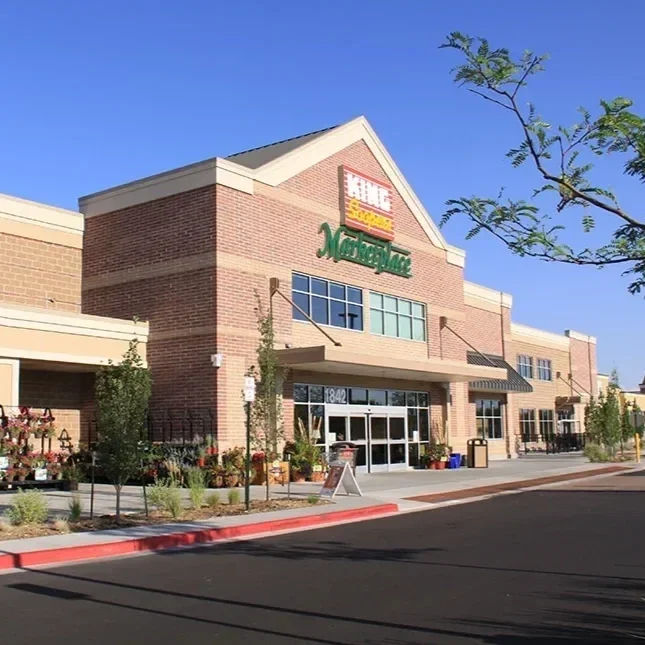 Exterior of a King Soopers Marketplace store on a sunny day, with the entrance, sidewalk, and parking lot visible in front.