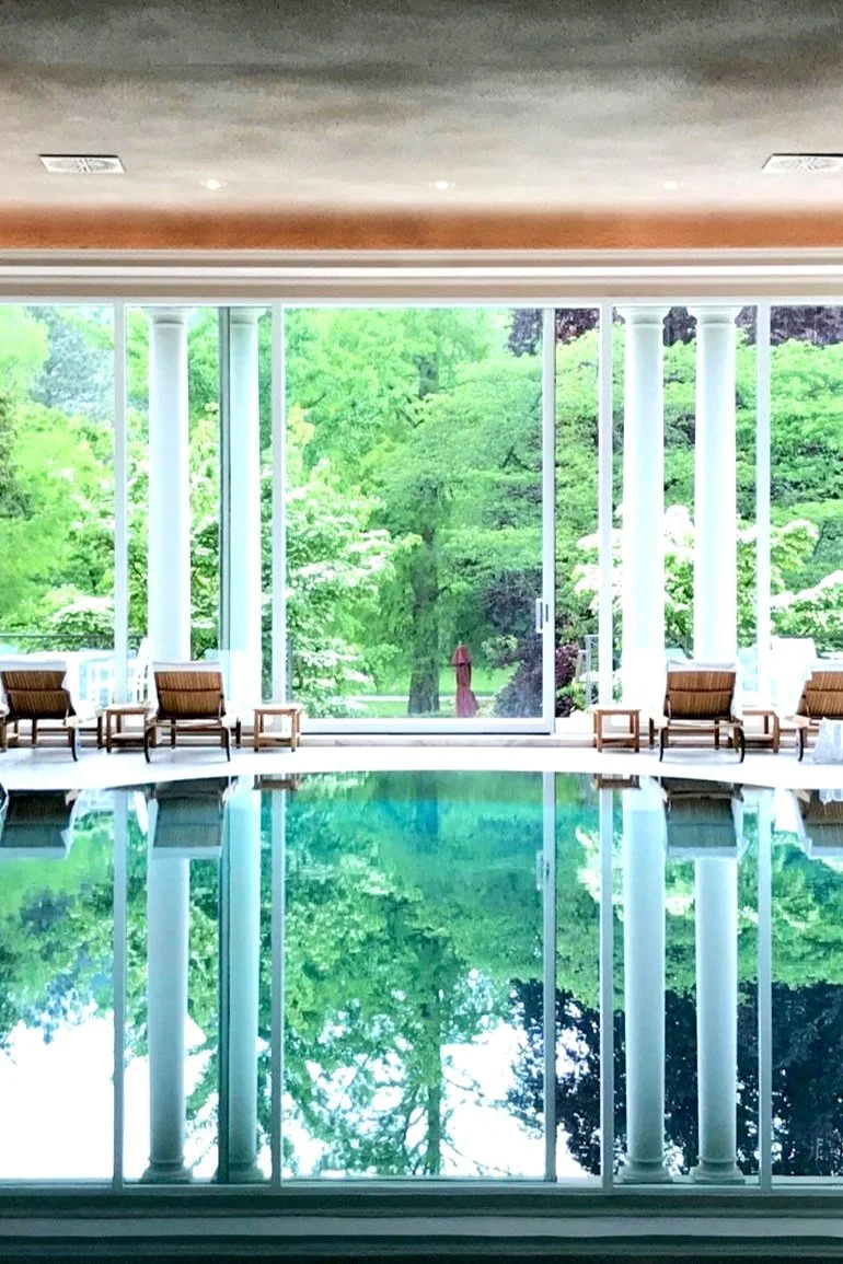 Best luxury day spas around th pool surrounded by lush greenery and elegant lounge chairs. Guests relax by the serene water, enjoying a tranquil atmosphere with soft lighting and stylish decor, creating a perfect oasis for relaxation and rejuvenation