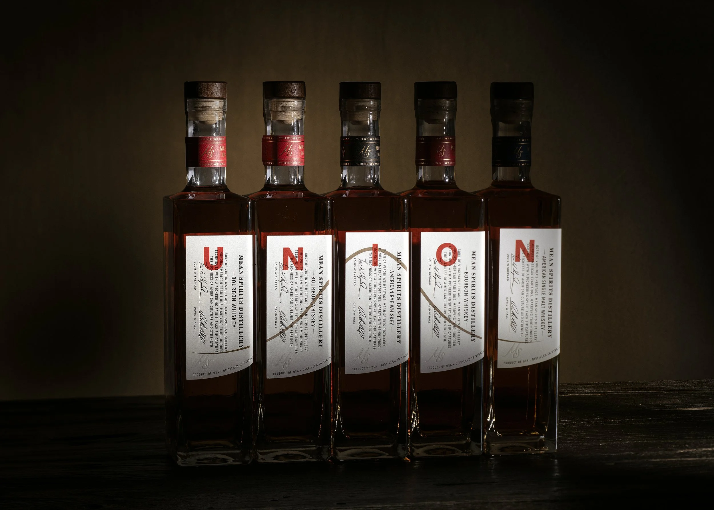 Mean Spirits Distillery Norfolk Virginia Bourbon lineup with sides of labels showcasing bell curve design