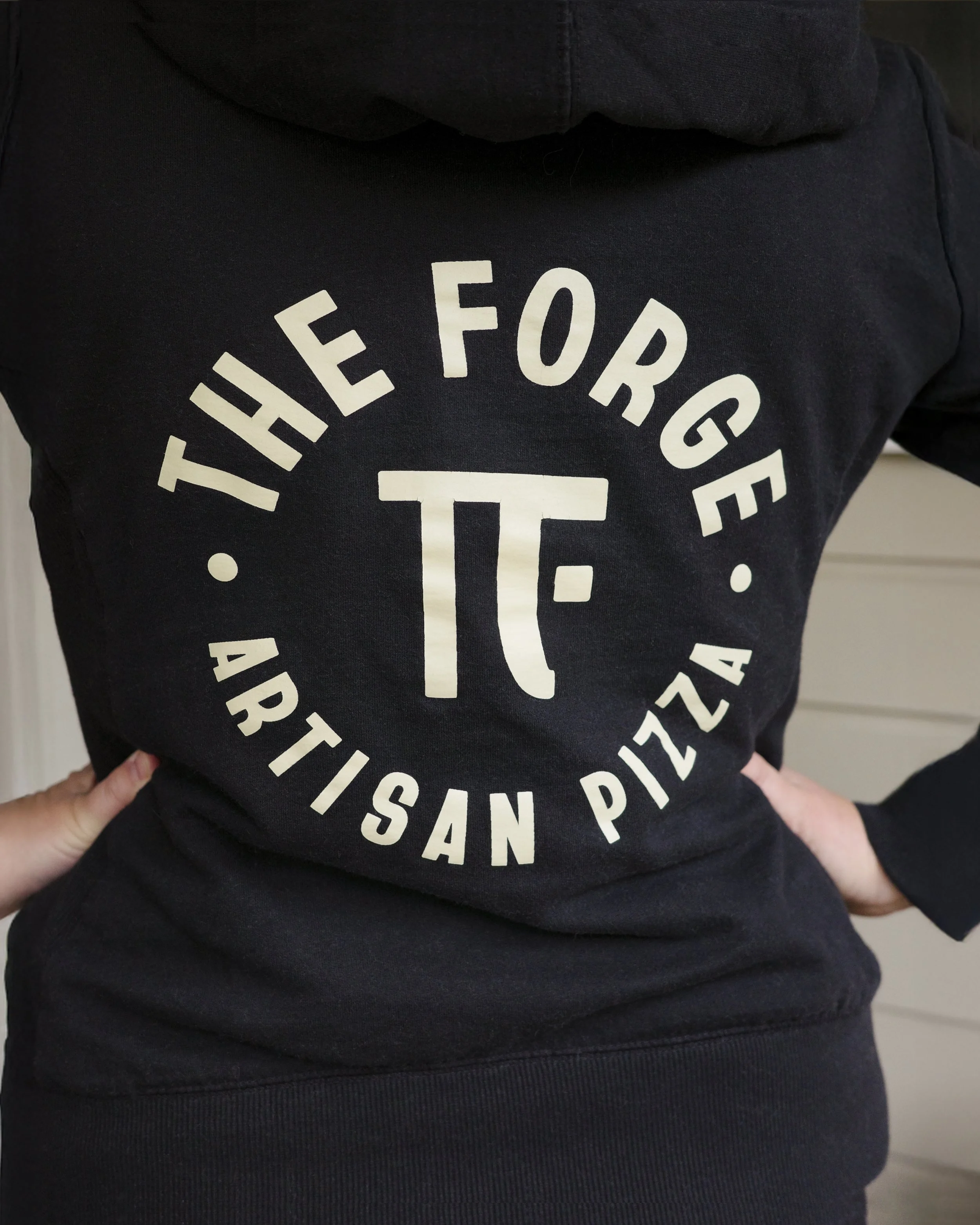 Close-up of a black hoodie with white circular text reading 'The Force' and a large 'T' in the center.