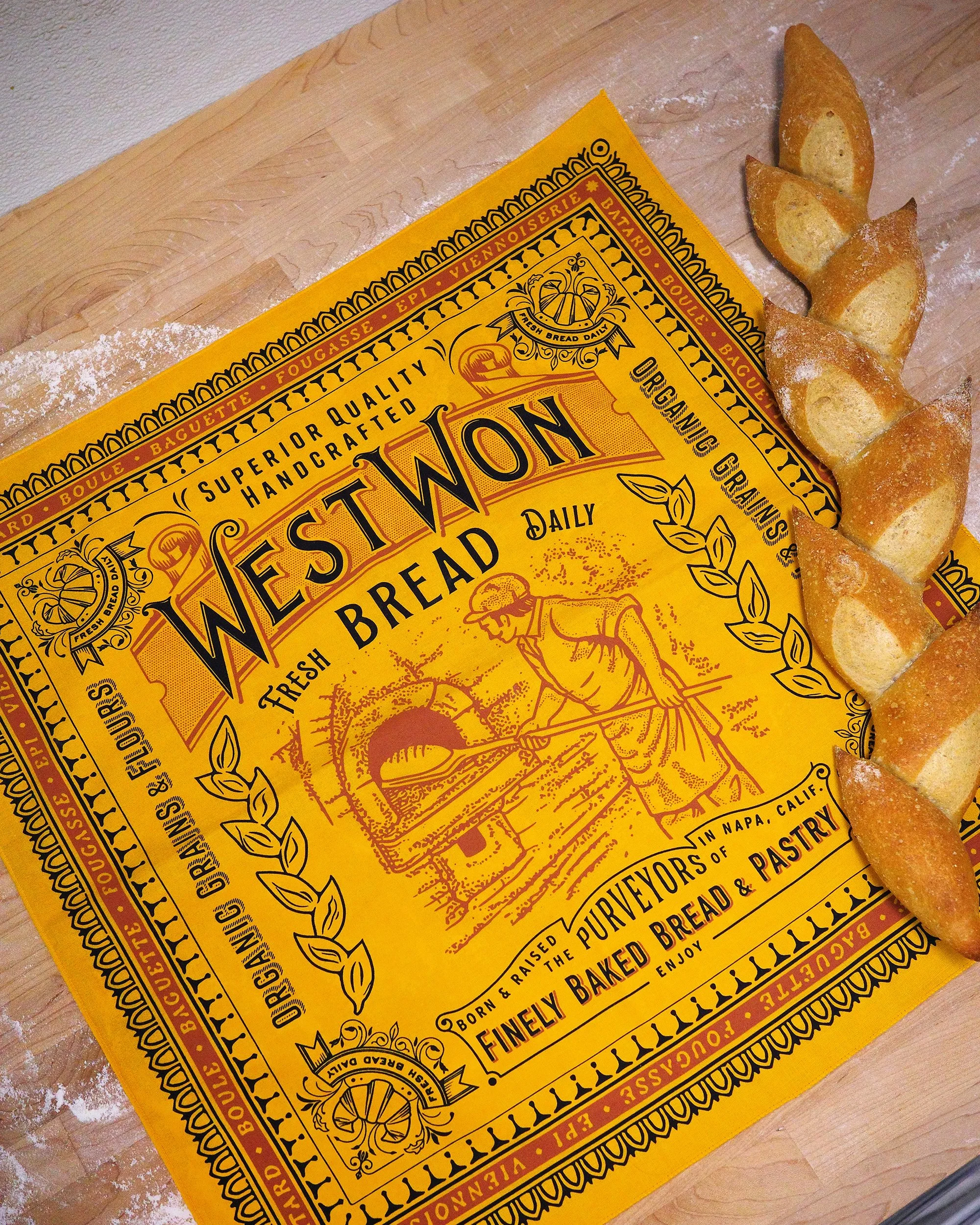 A package of sourdough bread and three slices on a wooden table. The package is yellow with black and red text, and the slices are dusted with flour.