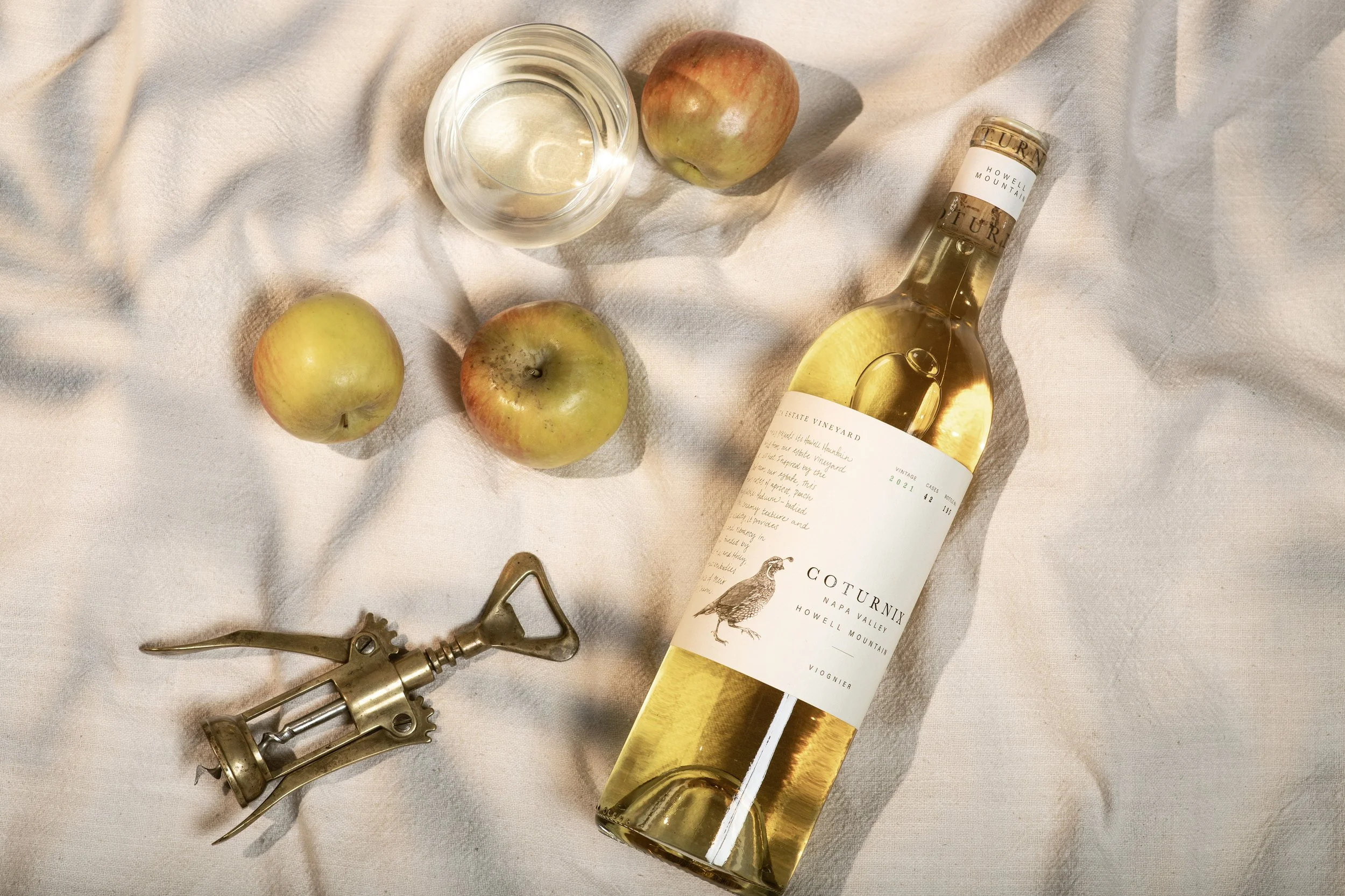 Coturnix Howell Mountain Napa Valley Viognier bottle with wine opener and apples on picnic blanket