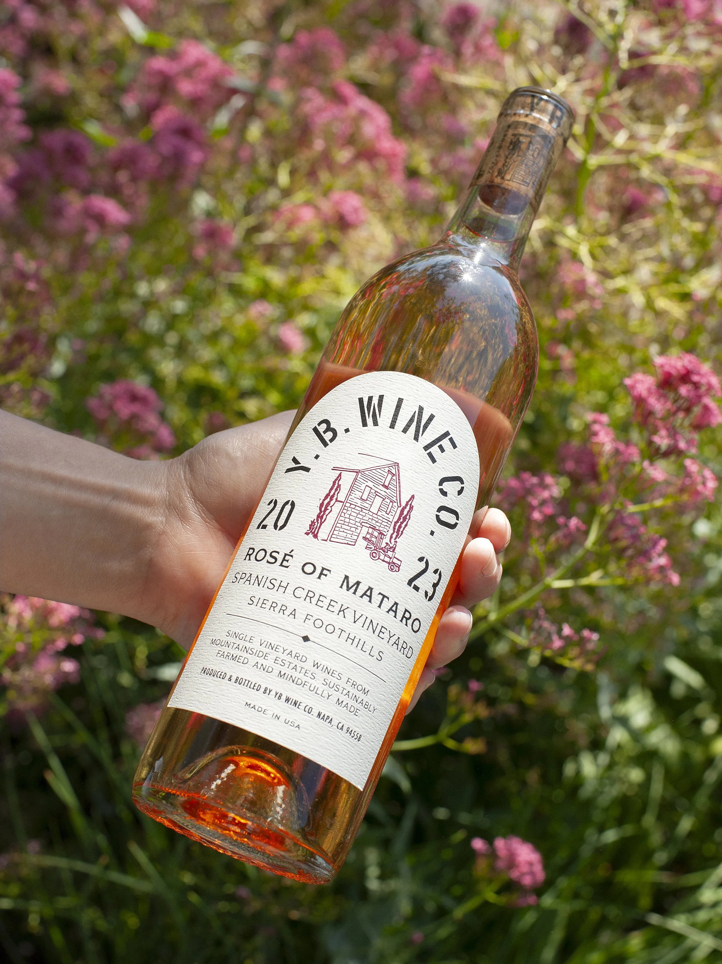 YB Wine Co Mount Veeder Napa Valley label being held in front of pink flowers