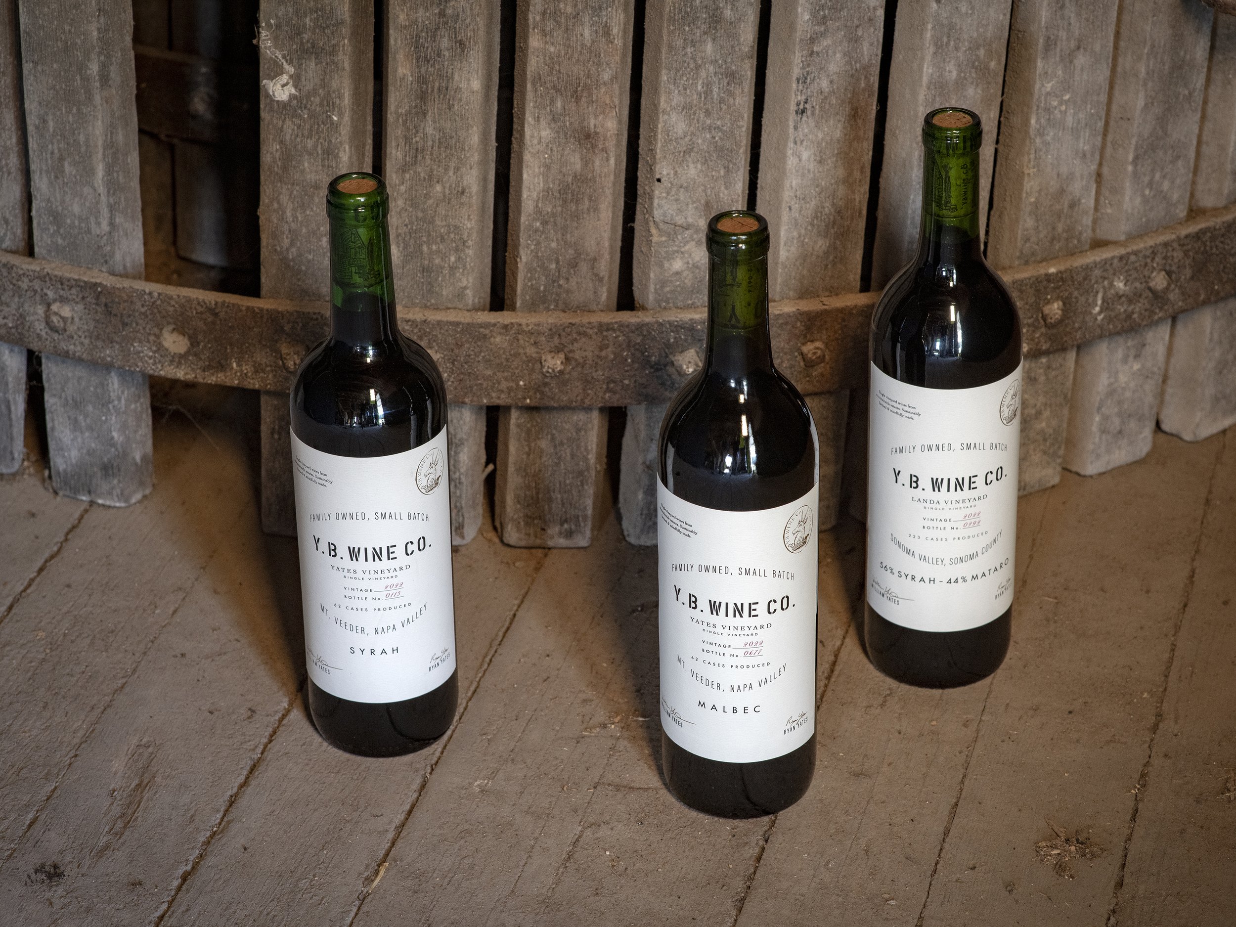 YB Wine Co Mount Veeder Napa Valley bottles sitting in front of barrel in barn