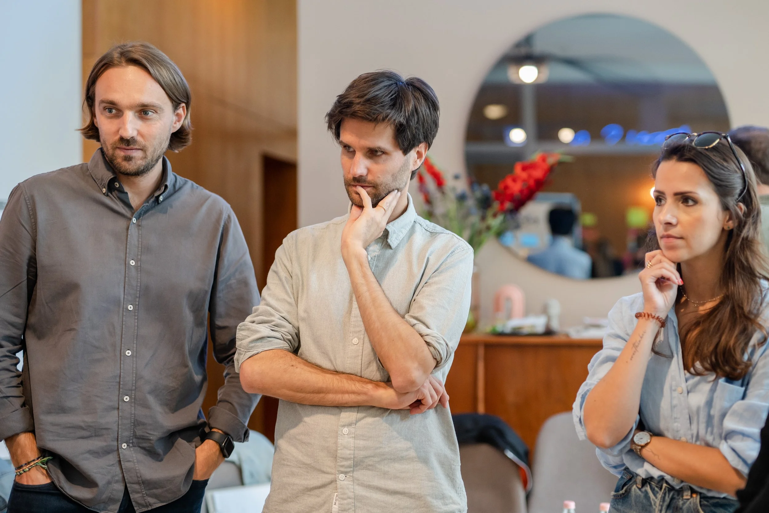 Drei Teammitglieder hören konzentriert zu, zwei mit der Hand am Kinn, in einer systemischen Teamcoaching-Session