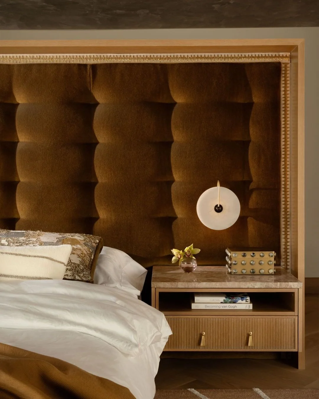 balancing bold architectural elements with soft, luminous details makes this home luxurious yet livable. the principal suite boasts a custom ochre velvet headboard that conceals wardrobe space behind it, a glossy venetian-plaster ceiling, and seamles