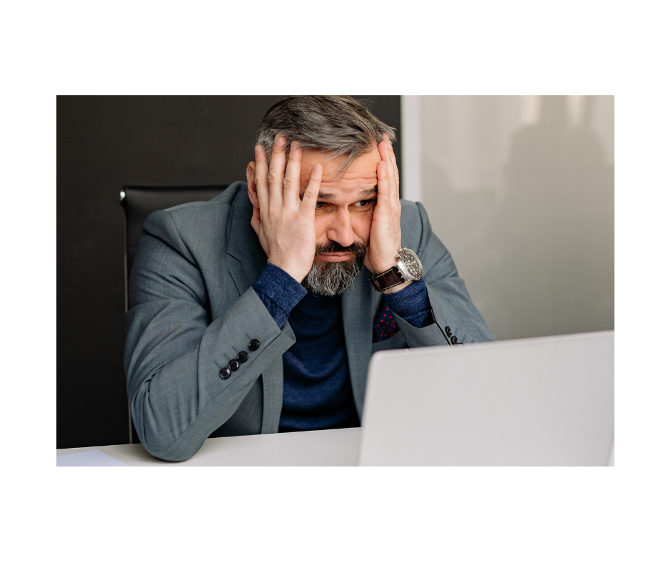 Man in grey business suit holds his head in his hands