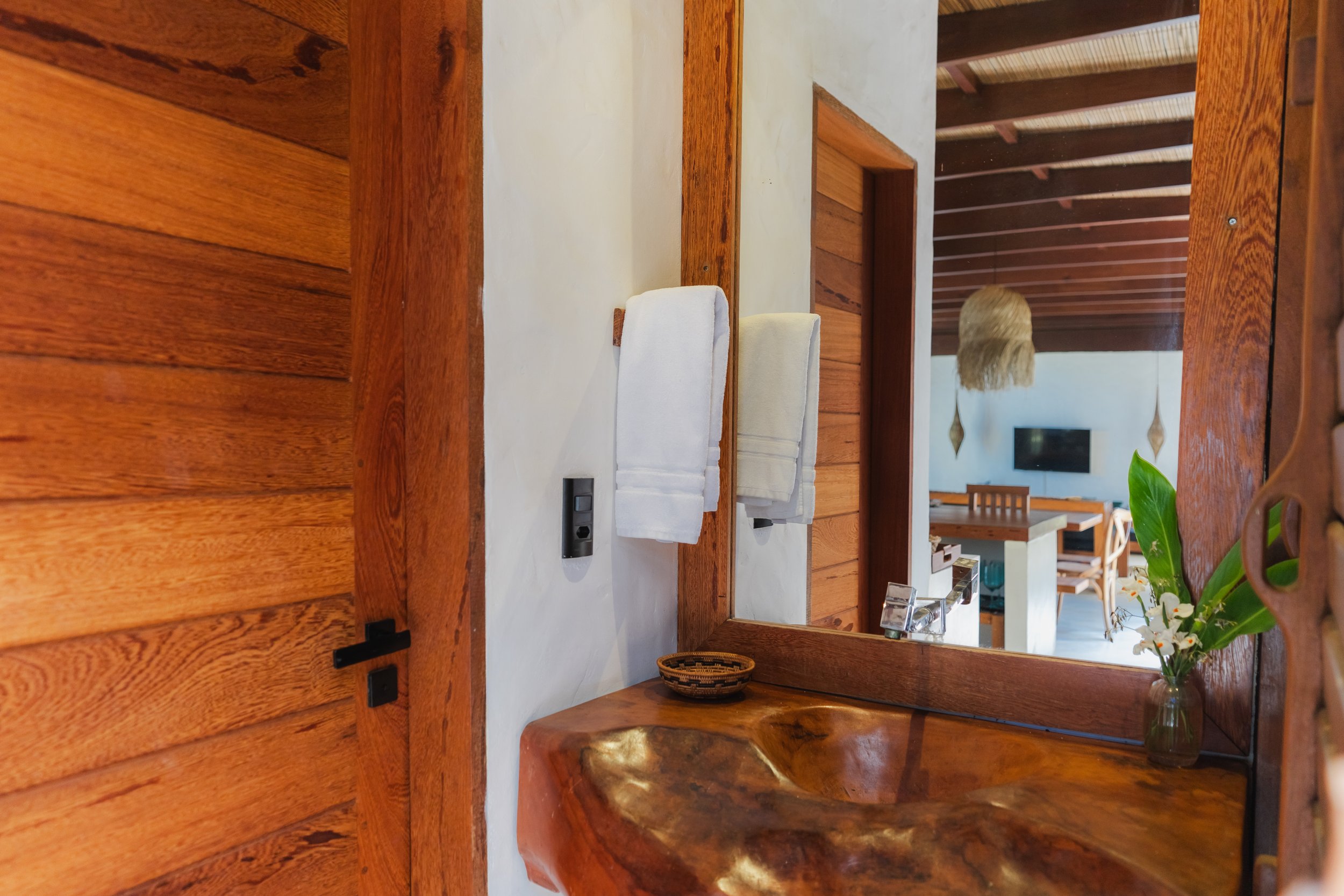 Reflexo de uma sala de jantar moderna com teto de madeira e televisão ao fundo