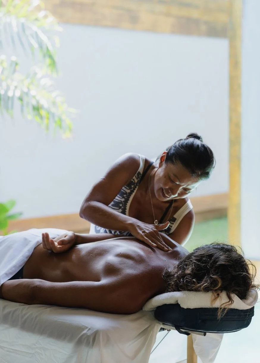 Pessoa recebendo massagem nas costas em uma maca, em ambiente iluminado e tranquilo.