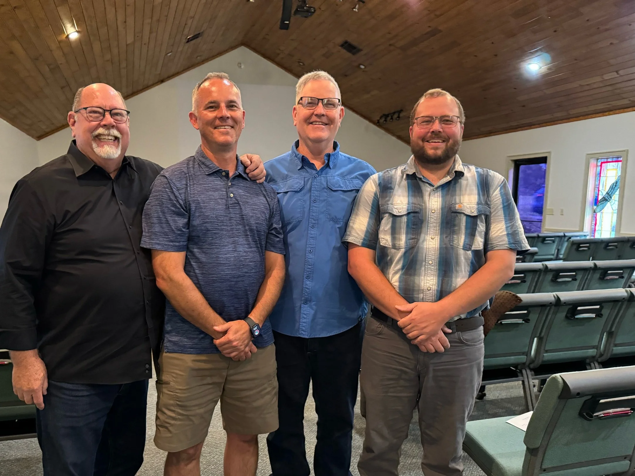 Picture of four men standing side by side as elders of Baptist church in sanctuary