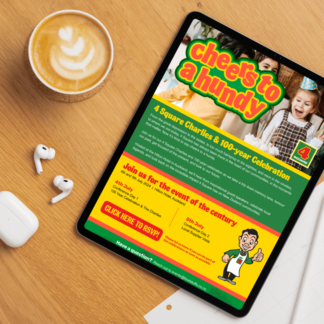 A digital tablet on a wooden table displays a colorful event flyer titled 'Cheers to a Humdy,' celebrating 100 years of 4 Square Charliess with images of children at a party. Next to the tablet, there is a cup of coffee with latte art and a pair of w