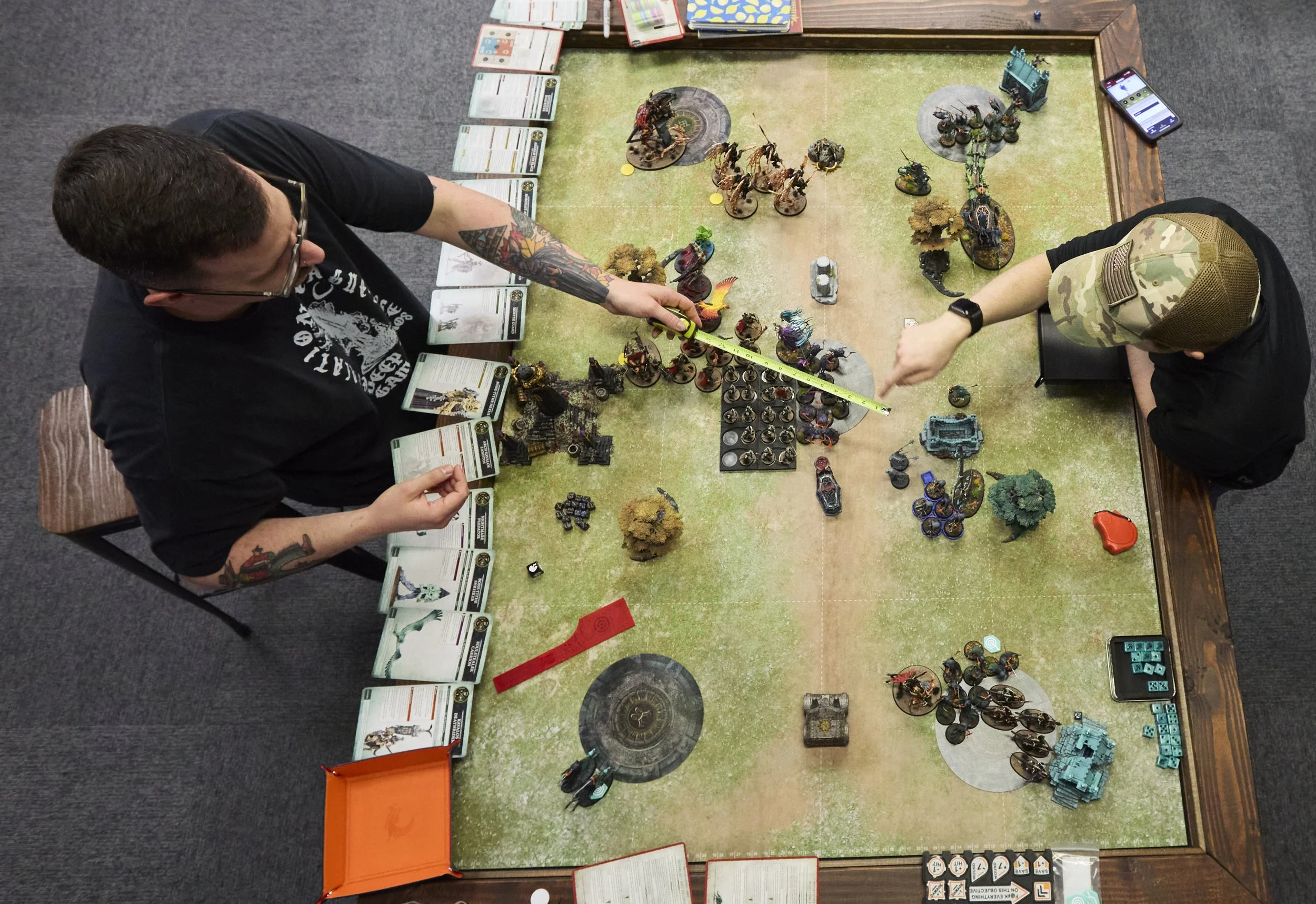 Left to right, Store owner Eric Smith and James Butcher play Warhammer at Deep Dive games in Athens, Ohio, on Oct 30, 2025.  As new players come in and learn new games, Smith says, “ The community we cultivate is based around positivity and friendlin