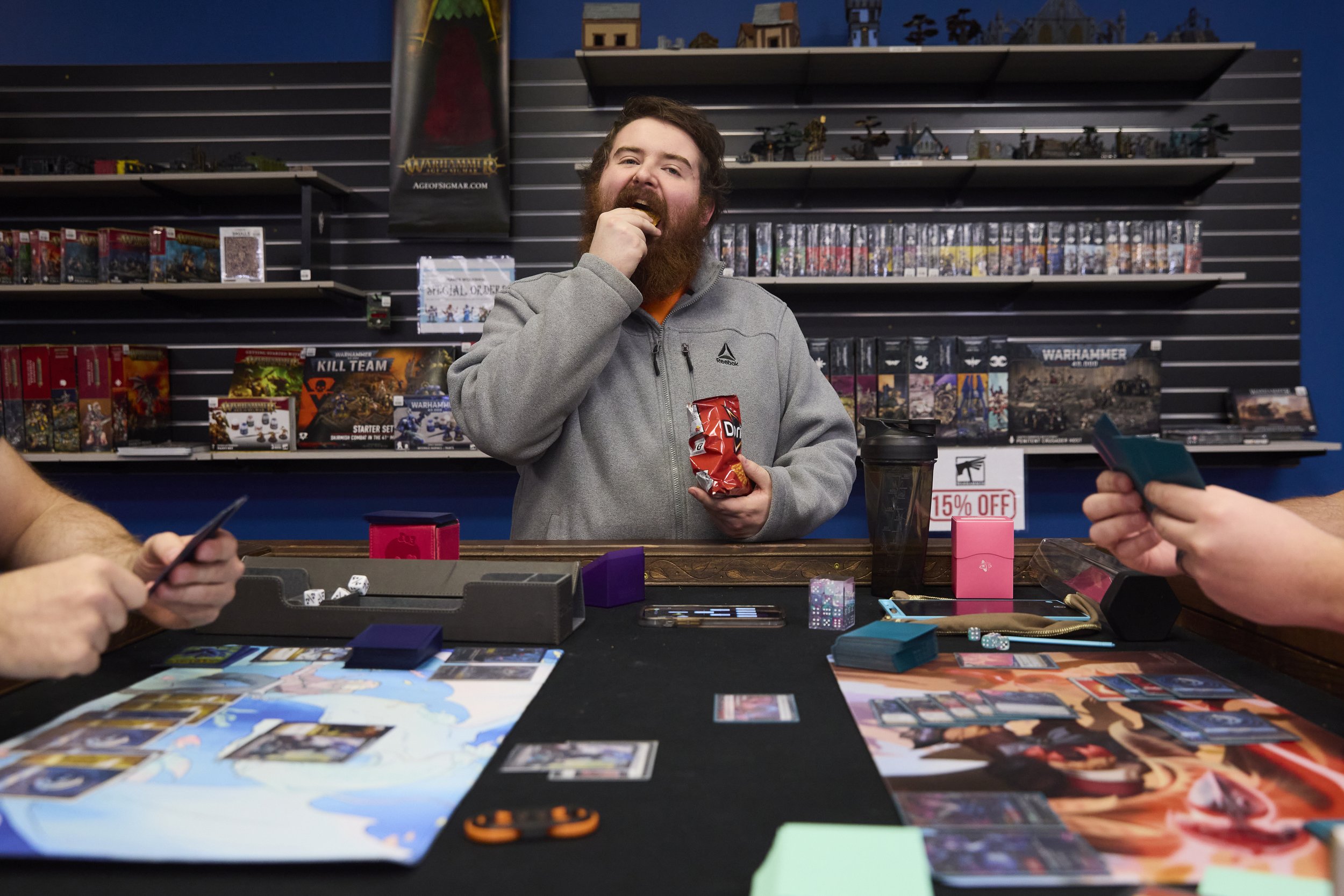 Brock Roush eats Doritos while waiting to play in the next Riftbound trading card game on Nov 2, 2025, at Deep Dive Games in Athens, Ohio. Riftbound was released on Oct 31, 2025, and a small community of players get together to play. 